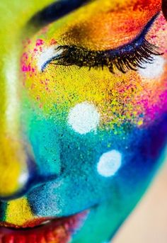 a woman's face with colorful makeup and eyeliners in the colors of rainbow