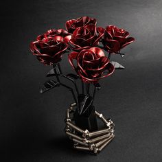 a vase filled with red roses on top of a black table next to a pair of scissors