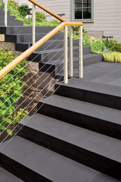 a set of stairs leading up to a house with plants growing on the railings