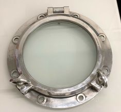 a metal porthole on the side of a white wall