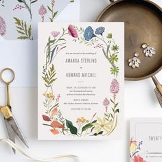 the wedding stationery is laid out on top of some other items, including a pair of scissors