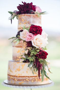 a wedding cake with red and white flowers on top is featured in this instagram