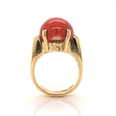 This beautiful Mid-Century cocktail ring features a cabochon cut red coral in 18 karat yellow gold. The coral has a medium scarlet red hue and is set in four golden prongs. The shoulders of the tapered band feature streamlined, openwork spaces for a bit of skin to peek through. From the profile, the Mid-Century details of the ring can truly be admired. The ring has a strong architecture and distinct style, finished in high polish 18k yellow gold. Modern Formal Cabochon Opal Ring, Formal Modern Opal Cabochon Ring, Modern Formal Opal Ring With Cabochon, Formal Fine Jewelry Signet Ring With Cabochon, Formal Cabochon Signet Ring, Classic Formal Cabochon Moonstone Ring, Formal 14k Gold Oval Cabochon Dome Ring, Formal Yellow Gold Ruby Ring With Cabochon, Formal Domed Signet Ring With Cabochon