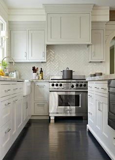 a kitchen with white cabinets and stainless steel stove top oven in the middle of the room