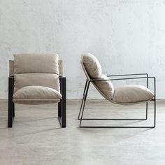 two chairs sitting next to each other in front of a white wall and cement floor