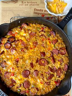 a skillet filled with cheese and pepperoni on top of a table next to chips