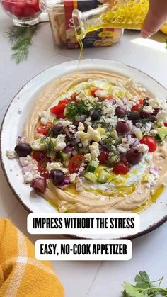 a white plate topped with hummus and veggies on top of a table