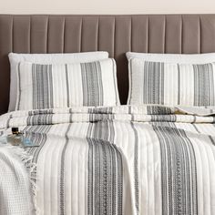 a bed with white and black striped bedspread on it's headboard