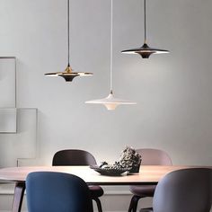 an image of a dining room setting with modern lighting fixtures hanging above the table and chairs