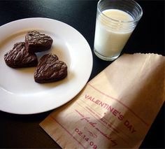 three cookies on a plate next to a glass of milk and napkins with writing