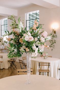 a vase filled with lots of flowers on top of a white table cloth covered table