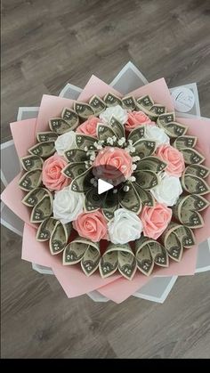 a bouquet of flowers made out of dollar bills on top of a wooden floor with pink and white paper