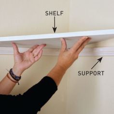 a person is holding their hands up to the shelf above them and pointing at it