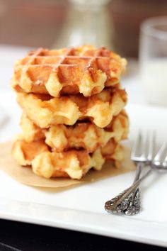 a stack of waffles sitting on top of a white plate next to a fork