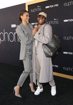 two people standing next to each other on a black carpet