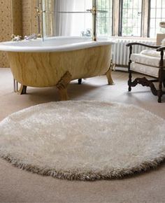 a bath tub sitting on top of a white rug in a bathroom next to a chair