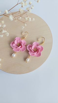 the pink flower earrings are on display next to some white flowers and branches in front of a