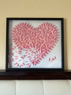 a heart made out of pink butterflies in a frame