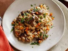 a white plate topped with mushroom riso and carrots next to a red napkin