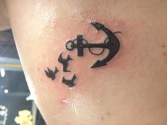 an anchor and birds tattoo on the back of a woman's shoulder