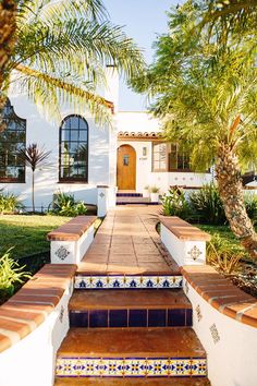 a white house with blue and red tiles on the steps leading to it's front door