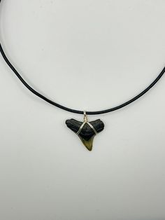 a black and green necklace on a white surface with a silver wire hanging from it