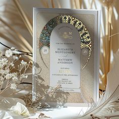 a wedding card with an ornate design on it and some flowers in the foreground