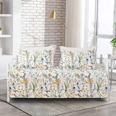 a living room with a white couch covered in pillows and floral print on the cover