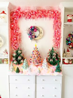 a decorated christmas tree in front of a white dresser with pink and green decorations on it