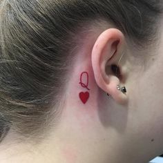 a woman's ear with a red heart tattoo on her left behind the ear