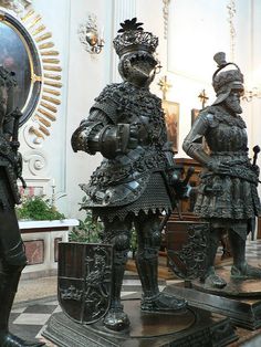 two statues of knights standing next to each other in front of a mirror and clock