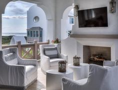 a living room filled with white furniture and a flat screen tv mounted to the wall