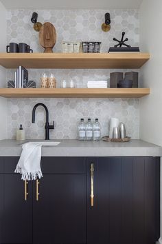 a kitchen with black cabinets and wooden shelves