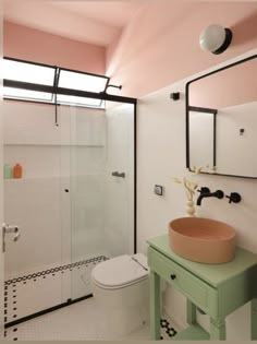 a bathroom with a sink, toilet and shower stall in the corner is painted pink