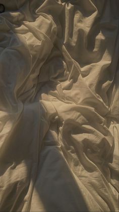 an unmade bed with white sheets and pillows