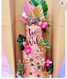 a pink and gold wedding cake with zebras, flowers, and fan on top