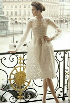 a woman in a white dress standing on a balcony