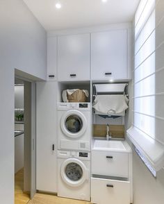 a washer and dryer in a small room with white cabinets on the wall