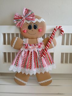 a gingerbread girl doll hanging on the wall with candy canes in her hand