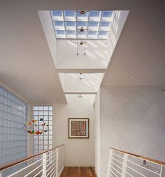 an empty hallway with wooden floors and skylight above the door to another room that has glass blocks on the walls