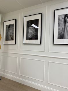 three black and white photographs hang on the wall next to a vase with flowers in it