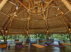 a bamboo structure with yoga mats on the floor and lights hanging from the rafters