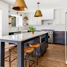 a kitchen with two stools and an island in the middle, surrounded by wooden flooring