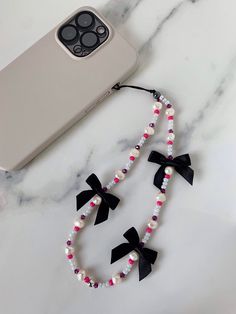 a cell phone is laying next to a necklace on a marble table with an iphone in the background