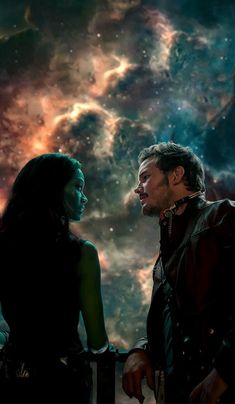 a man standing next to a woman in front of a space filled with stars and clouds