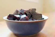 a blue bowl filled with chocolate pieces on top of a wooden table