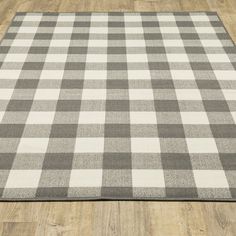 a gray and white checkered rug is on the floor in front of a wooden floor