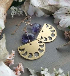 "These lovely, lightweight earrings feature beautiful, top-grade Fluorite gems with shades of purple, lavender, clear, and aqua and sparkly, lilac crystals. The flashy gemstones are finished with a warm brass, half-circle charms with cutouts of the phases of the moon. They measure approximately 2\" long x just under 1.25\" wide and the earwires are hypo-allergenic, 10kt gold-filled. Please note: these earrings are made-to-order and there may be slight variations from pair to pair. Thanks for che Adjustable Purple Moon Phase Jewelry, Purple Adjustable Celestial Jewelry, Adjustable Purple Celestial Jewelry, Handmade Purple Crescent Jewelry, Bohemian Purple Moon Phase Jewelry, Purple Bohemian Everyday Jewelry, Celestial Amethyst Moon Phase Jewelry, Celestial Moon Phase Amethyst Jewelry, Handmade Purple Moon-shaped Jewelry