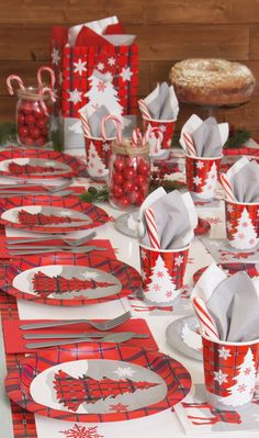 a table set up for christmas with red and white paper cups, candy canes, napkins and candies