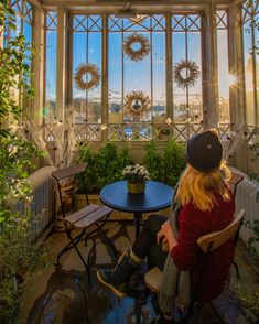 two people sitting at a table in front of large windows with wreaths on them